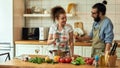 Young couple preparing a meal together in the kitchen. Italian man, chef cook looking at his girlfriend, holding a glass Royalty Free Stock Photo