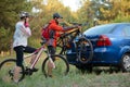 Young Couple Unmounting Mountain Bikes from Bike Rack on the Car. Adventure and Family Travel Concept. Royalty Free Stock Photo