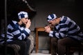 Young couple of prisoners sitting near bedside table and praying