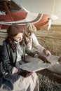 Young couple with private plane looking at map, vertical