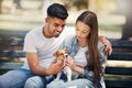 Young couple, puppy and relax in park, bench and summer sunshine with happiness, care and bonding. Man, woman and small Royalty Free Stock Photo