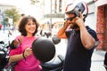 Young couple putting on helmet to ride a motorcycle