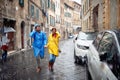 A young couple in raincoats on the street is running to hide from the rain. Walk, rain, city, relationship Royalty Free Stock Photo