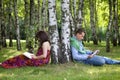 Young couple reading books in park by tree trunk Royalty Free Stock Photo