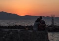 Young couple rear view hugging tenderly girl leaned on boy`s shoulder watching the sunset and sea in greece Royalty Free Stock Photo