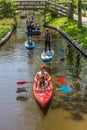 Young couple in a red canoe goeing through the historic canal of Giethoorn