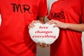 Young couple in red shirts holding white fabric heart with text Royalty Free Stock Photo