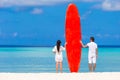 Young couple with red surfboard on white beach Royalty Free Stock Photo