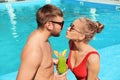 Young couple with refreshing cocktails near swimming pool