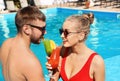 Young couple with refreshing cocktails near swimming pool