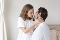 Young couple in a relationship kissing and cuddling. Happy couple hug and kiss on the bed near the window in the morning. Royalty Free Stock Photo