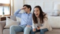 Young couple relax on sofa disagree on TV channel