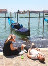 A young couple relax at the water`s edge near St. Mark`s Square in Venice