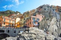 A young couple relaxes on the rocks above the swimming harbor of Manarola, Italy,