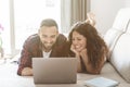 Young couple relaxes on the sofa browsing and shopping online with laptop - engaged couple has fun with notebook making video Royalty Free Stock Photo