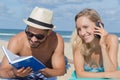 young couple relaxing on beach with book and phone Royalty Free Stock Photo