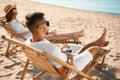 Young couple relaxing in deck chairs on beach Royalty Free Stock Photo