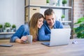 Young couple relaxing drinking a coffee and using the computer laptop around cardboard boxes, very happy moving to a new house Royalty Free Stock Photo