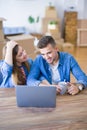 Young couple relaxing drinking a coffee and using the computer laptop around cardboard boxes, very happy moving to a new house Royalty Free Stock Photo