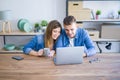 Young couple relaxing drinking a coffee and using the computer laptop around cardboard boxes, very happy moving to a new house Royalty Free Stock Photo