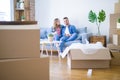 Young couple relaxing drinking a cup of coffee sitting at sofa of  new home with cardboard boxes around them, very happy moving to Royalty Free Stock Photo