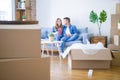 Young couple relaxing drinking a cup of coffee sitting at sofa of  new home with cardboard boxes around them, very happy moving to Royalty Free Stock Photo