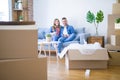 Young couple relaxing drinking a cup of coffee sitting at sofa of  new home with cardboard boxes around them, very happy moving to Royalty Free Stock Photo