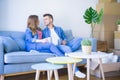 Young couple relaxing drinking a cup of coffee sitting at sofa of  new home with cardboard boxes around them, very happy moving to Royalty Free Stock Photo