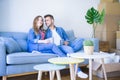 Young couple relaxing drinking a cup of coffee sitting at sofa of  new home with cardboard boxes around them, very happy moving to Royalty Free Stock Photo