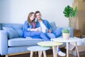 Young couple relaxing drinking a cup of coffee sitting at sofa of  new home with cardboard boxes around them, very happy moving to Royalty Free Stock Photo