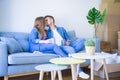 Young couple relaxing drinking a cup of coffee sitting at sofa of  new home with cardboard boxes around them, very happy moving to Royalty Free Stock Photo