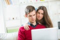 Young couple relaxing on sofa with laptop in the living room. Royalty Free Stock Photo
