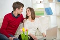 Young couple relaxing on sofa with laptop in the living room. Royalty Free Stock Photo