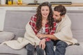 Young couple relaxing in their apartment, lying on the couch, watching a movie. Royalty Free Stock Photo