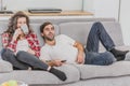 Young couple relaxing in their apartment, lying on the couch and watching the movie. The lens is the effect of glare on Royalty Free Stock Photo