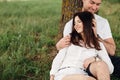 Young couple relaxing under tree in park on sunny day. Happy couple in love spend time outdoors together. Handsome man and pretty Royalty Free Stock Photo