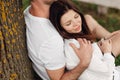 Young couple relaxing under tree in park on sunny day. Happy couple in love spend time outdoors together. Handsome man and pretty Royalty Free Stock Photo