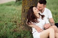 Young couple relaxing under tree in park on sunny day. Happy couple in love spend time outdoors together. Handsome man Royalty Free Stock Photo