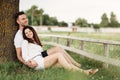 Young couple relaxing under tree in park on sunny day. Happy couple in love spend time outdoors together. Handsome man and pretty Royalty Free Stock Photo