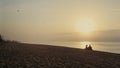 Young couple resting on beach at sunset. Wide shot lovers dating at ocean coast Royalty Free Stock Photo