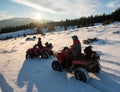 Young couple riders on four-wheelers ATV bikes on snow, enjoying sunset in the the mountains in winter Royalty Free Stock Photo