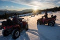 Young couple riders on off-road quad bikes, enjoying beautiful sunset in the the mountains in winter Royalty Free Stock Photo