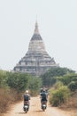 Young couple riding electric scooter towards Shwesandaw pagoda of ancient Bagan in Myanmar