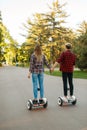 Young couple riding on gyroboard in park, back view