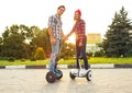 Young couple riding hoverboard - electrical scooter, personal ec