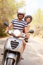 Young Couple Riding Motor Scooter Along Country Road