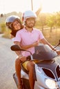 Young Couple Riding Motor Scooter Along Country Road Royalty Free Stock Photo