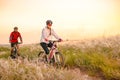 Young Couple Riding Mountain Bikes in the Beautiful Field of Feather Grass at Sunset. Adventure and Family Travel. Royalty Free Stock Photo