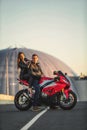 Young couple riding the red sports motorcycle at bridge on sunrise Royalty Free Stock Photo