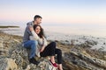 Young couple at rocky seacoast in sunset